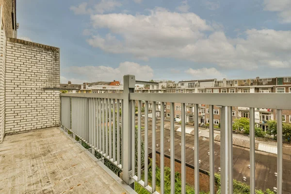 Panoramic view of brick buildings with parking and trees from small balcony