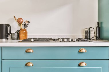 Minimalist tarzı mavi mobilyalı, lavabolu ve sobalı bir ev mutfağı.