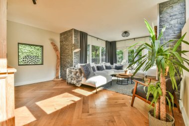 Çağdaş dairenin geniş odasındaki dinlenme odası ve mutfağın yakınındaki sandalyeli ve çiçekli masa.