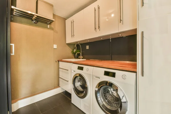 stock image Interior of modern bright laundry room with cupboard and dark reflect floor