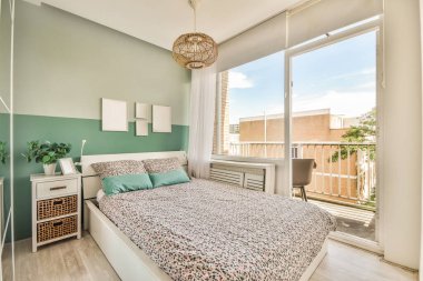 Balkon kapısının yanında rahat bir yatak, evdeki rahat yatak odasında perdeler var.