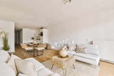 Günümüz minimalist tasarımı. Hafif stüdyo dairesinin ahşap masası ve oturma odası ile beyaz duvarları ve parke zemini arasında yemek masası ve sandalyeleri var.