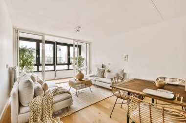 Günümüz minimalist tasarımı. Hafif stüdyo dairesinin ahşap masası ve oturma odası ile beyaz duvarları ve parke zemini arasında yemek masası ve sandalyeleri var.