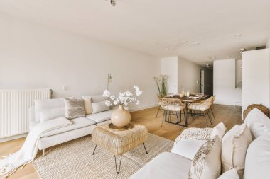 Günümüz minimalist tasarımı. Hafif stüdyo dairesinin ahşap masası ve oturma odası ile beyaz duvarları ve parke zemini arasında yemek masası ve sandalyeleri var.