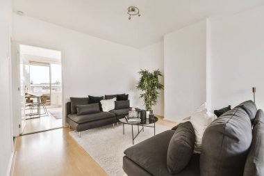 Günümüz minimalist tasarımı. Hafif stüdyo dairesinin ahşap masası ve oturma odası ile beyaz duvarları ve parke zemini arasında yemek masası ve sandalyeleri var.