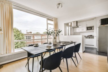 Günümüz minimalist tasarımı. Hafif stüdyo dairesinin ahşap masası ve oturma odası ile beyaz duvarları ve parke zemini arasında yemek masası ve sandalyeleri var.