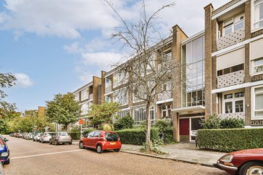 Arabaları, ağaçları ve fenerleri olan boş bir kaldırımdan panorama manzaralı evler.