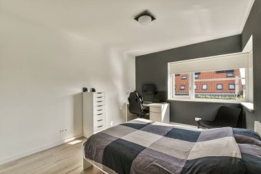 Kareli battaniyeyle kaplı rahat bir yatak ve modern dairenin aydınlık yatak odasında.