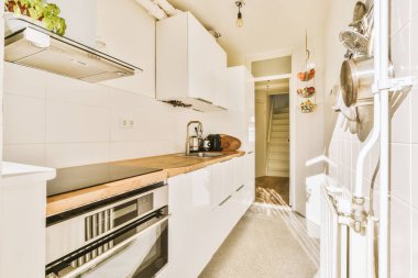 Minimalist tarzı beyaz mobilyalı, lavabolu ve sobalı bir ev mutfağı.