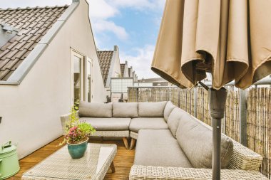 Metal parmaklıklı dar tuğla balkon, tahta sandalye ve camlı kapı mutfağa açılıyor.