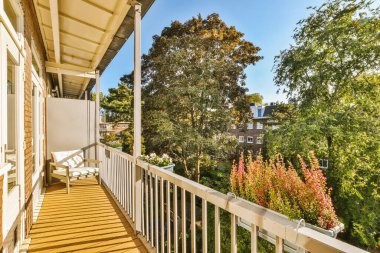 Metal parmaklıklı dar tuğla balkon, tahta sandalye ve camlı kapı mutfağa açılıyor.