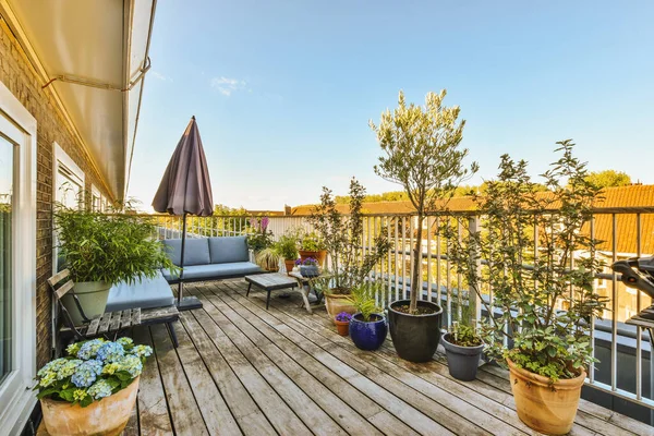 stock image Bright brick balcony with metal railings, wooden chair and door