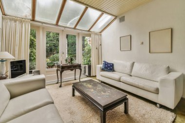 Yastıklı rahat bir kanepe TV ve teras kapılı modern aşk odasında süslemeleri olan ışıklı bir duvara dayanıyor.