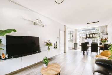 Günümüz minimalist tasarımı. Hafif stüdyo dairesinin ahşap masası ve oturma odası ile beyaz duvarları ve parke zemini arasında yemek masası ve sandalyeleri var.