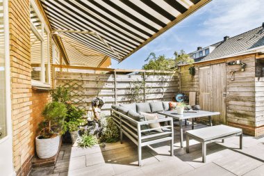 Neat paved patio with sitting area and small garden near wooden fence