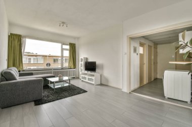 Modern apartmandaki dekorasyonlu ve televizyonlu rahat kanepenin yanındaki masa ve vazo.