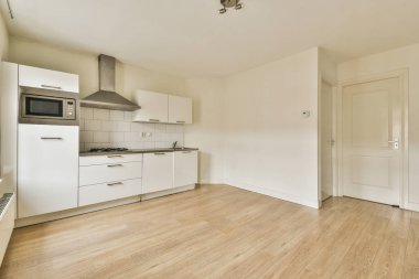 Pencerelerin yanında dolapları ve aletleri olan boş aydınlık mutfağın içi