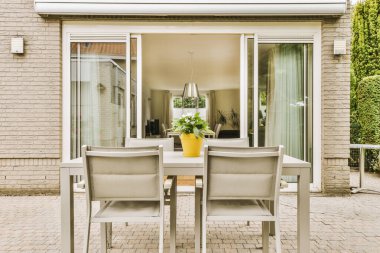 Oturma alanı ve ahşap çitlerin yanındaki küçük bahçesi olan düzgün asfaltlı bir avlu.