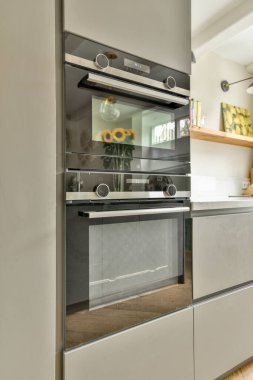 Çağdaş dairenin geniş odasındaki dinlenme odası ve mutfağın yakınındaki sandalyeli ve çiçekli masa.