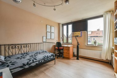 Comfortable bed with white bedclothes and bedside table with lamp placed near window in light bedroom at home