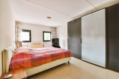 Yatak odasının iç tasarımı, yatak odası ve ahşap gardırop modern dairenin penceresinin kenarına yerleştirilmiş.