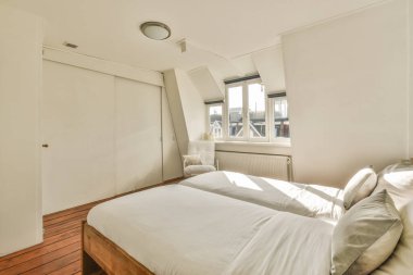 Modern minimalist tarzda pencereli Mansard yatak odasındaki beyaz duvarın yanına konforlu yatak