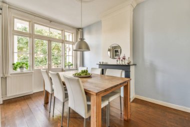 Stüdyo dairesinin modern minimalist tarzı iç tasarımı açık beyaz mutfak ve yemek masası ve sandalyeleri tavan arası lambasıyla aydınlatılmış.