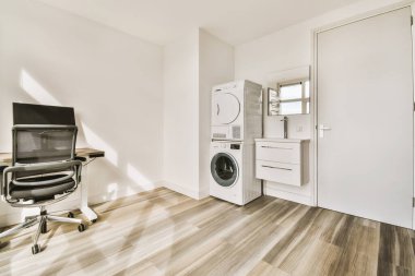 Çamaşır makinesi, kurutma makinesi ve çamaşır makinesi olan bir çamaşır odası kapının önünde.