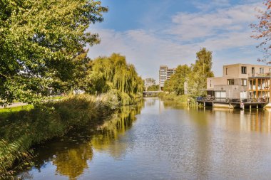 Öteki tarafında evler olan bir nehir ve su kenarında ağaçlar olan bir nehir.