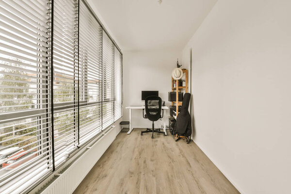 a home office with wood flooring and white shutters on the windows looking out onto an outside patio area
