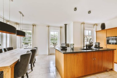 Günümüz minimalist tasarımı. Hafif stüdyo dairesinin ahşap masası ve oturma odası ile beyaz duvarları ve parke zemini arasında yemek masası ve sandalyeleri var.