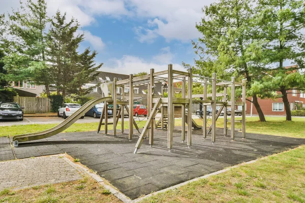 an outdoor play area with playground equipment and cars parked in the background at camden place apartments in baltimore, maryland