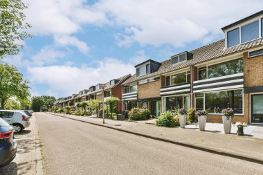 Arabaları, ağaçları ve fenerleri olan boş bir kaldırımdan panorama manzaralı evler.