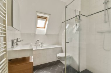 Evdeki modern tuvalette asılı duran banyo musluğu ile duvar arasındaki cam bölme.