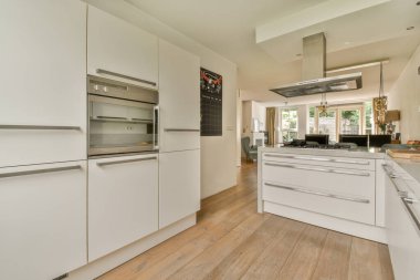 Çağdaş dairenin geniş odasındaki dinlenme odası ve mutfağın yakınındaki sandalyeli ve çiçekli masa.