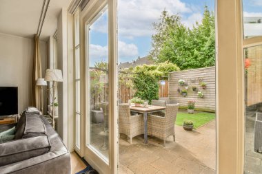 Çağdaş dairenin geniş odasındaki dinlenme odası ve mutfağın yakınındaki sandalyeli ve çiçekli masa.