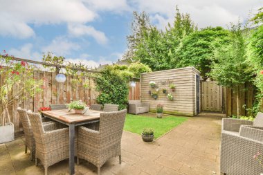 Neat powerful patio with sitting area and small garden near wooden fence