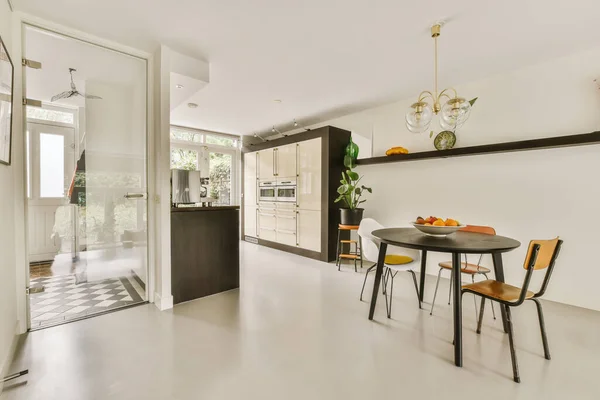 a kitchen and dining area in a house with white walls, wood flooring and black accents on the wall