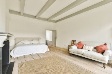 Geniş yatak odasındaki televizyon ve şöminenin yanındaki rahat yatağı ve kanepesi olan modern bir yatak.