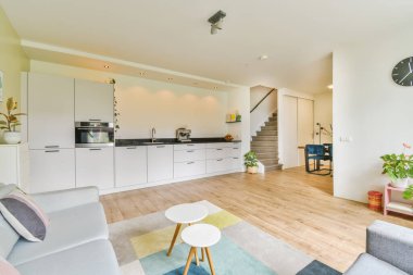 Odanın her iki tarafında ahşap döşemeli ve beyaz dolaplı bir oturma odası var.