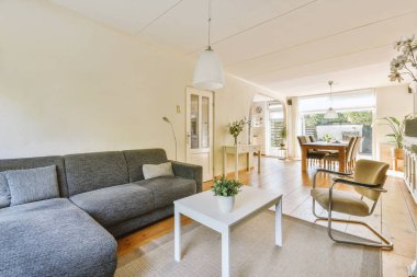 Günümüz minimalist tasarımı. Hafif stüdyo dairesinin ahşap masası ve oturma odası ile beyaz duvarları ve parke zemini arasında yemek masası ve sandalyeleri var.