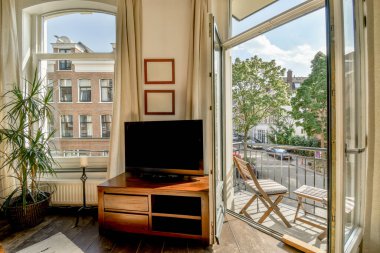 Çağdaş dairenin geniş odasındaki dinlenme odası ve mutfağın yakınındaki sandalyeli ve çiçekli masa.