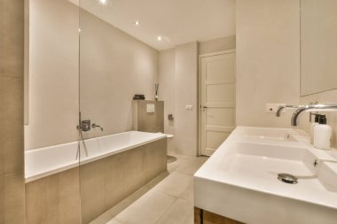 Odanın ortasında lavabo ve küveti olan bir banyo duvarda bir ayna var.