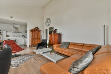 Turuncu deri koltukları olan bir oturma odası ve odanın duvarında eski bir saat çok temiz.