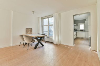 Çağdaş evdeki mutfak ve kapıya parlayan lambaların altına konmuş sandalyeli ve çiçekli masa.