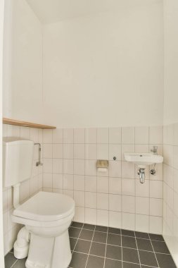 Lavabolu, tuvaletli, beyaz duvarlı ve kareli küçük bir tuvalet.