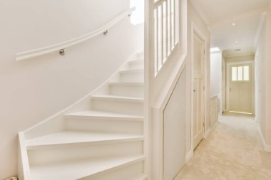 Merdivenlerde kimse olmayan bir evde beyaz bir merdiven ve başka bir odaya açılan açık bir kapı.