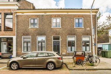 Evin önüne park etmiş bir araba, yanında iki bisiklet ve duvara yaslanmış bir bisiklet.