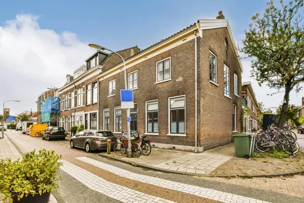an old brick building in the netherlands, with bicycles parked on the street next to it and two cars parked outside