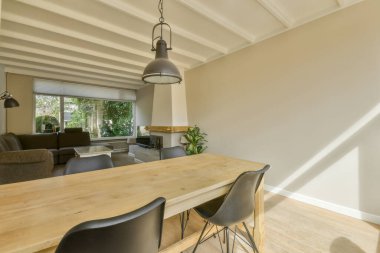 Çağdaş dairenin geniş odasındaki dinlenme odası ve mutfağın yakınındaki sandalyeli ve çiçekli masa.